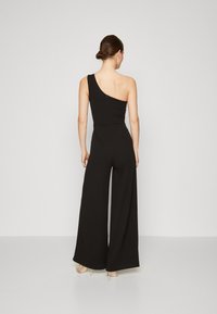 Svart, en-skulder jumpsuit med en tettsittende bodice og vide bukser. Glatt tekstur, glidelås i ryggen, minimale design detaljer.