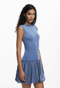 Blaues Denim-Kleid mit ärmellosem Design, taillierter Oberweite, rundem Ausschnitt und gerafftem Rock. Hergestellt aus strukturiertem Stoff mit glatter Oberfläche.