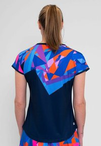 Camiseta atlética de manga corta con un patrón geométrico en azul, rosa y naranja. Cuerpo texturizado en azul marino con acentos coloridos en los hombros y la espalda.