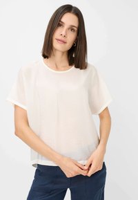 Hvid, kortærmet bluse i let, let struktureret stof med rund halsudskæring og kontrastkanter. Fitted, afslappet silhuet.