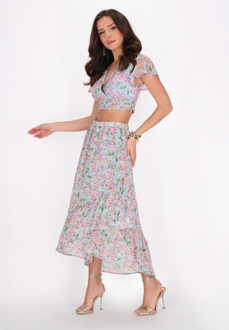 Bloemrijk tweedelig outfit met een cropped top met fladdermouwen en een lange, vloeiende rok. Lichtblauwe stof met roze en groene patronen.