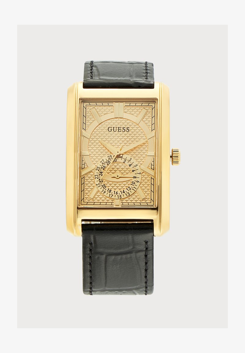 Ορθογώνιο ρολόι Guess με χρυσή απόχρωση, κεντραρισμένο διακοσμημένο καντράν, χρυσά δείκτες, μαύρο δερμάτινο λουράκι και στρογγυλή ένδειξη ημερομηνίας στο κάτω κέντρο.