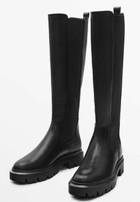 Bottes montantes en cuir noir avec une finition lisse, des panneaux latéraux élastiques et des semelles épaisses à motif cramponné.