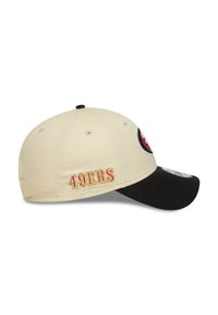 Căciulă de baseball bej cu vizieră neagră, cu broderia "49ERS" în roșu pe lateral și un patch cu logo pe față. Material din bumbac.
