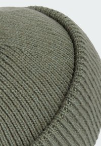 Stickad grön ullmössa med ribbad textur och slät topp; har ett något mörkare band i kanten för ökad struktur.