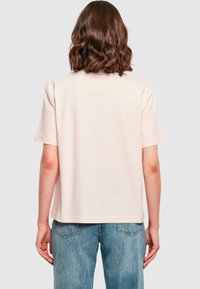 Kortærmet, pastel pink T-shirt lavet af bomuld med en afslappet pasform. Har en lige kant og minimale sømdetaljer ved kraven.