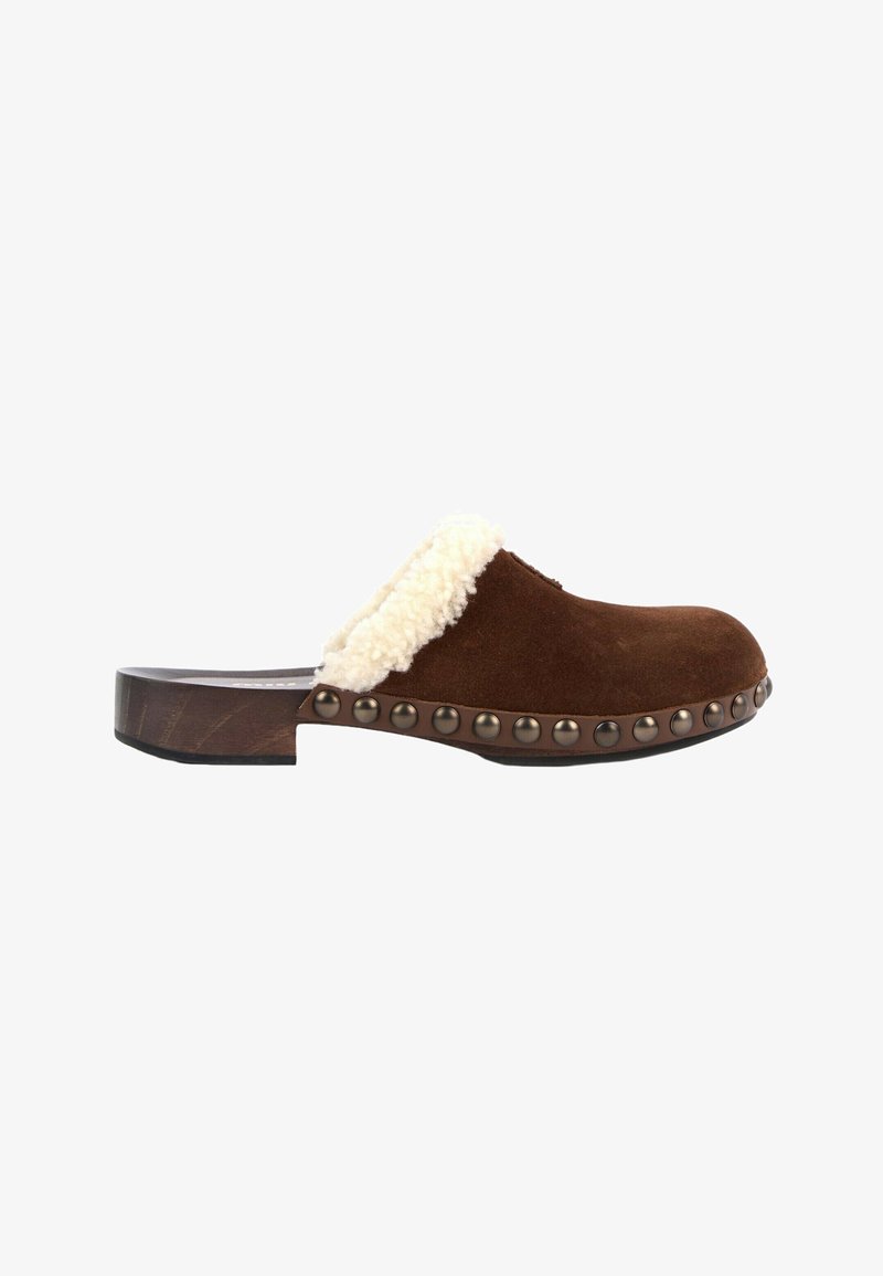 Sabot marron en daim à enfiler avec une doublure en shearling crème, talon en bois, et clous métalliques le long du bord de la semelle, vu de côté.