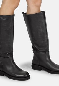 Botas de cuero negras hasta la rodilla con una textura suave, puntera redonda, tacón bajo y apilado, y diseño holgado. Apariencia simple y elegante.