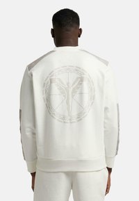 Weißer Sweatshirt mit einem großen, dezenten Grafik eines Figures und einem kreisförmigen Muster auf dem Rücken; verfügt über kontrastierende, texturierte Schulternpaneele.