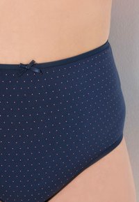 Culotte taille haute bleu marine en tissu doux avec de petits pois roses et un nœud décoratif à la taille.