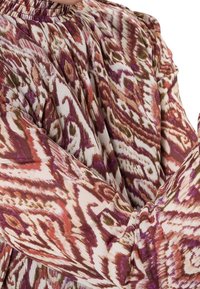Blouse à manches longues en tissu léger avec un motif tourbillonnant dans des nuances de marron, violet et crème ; décolleté froncé et finition texturée.