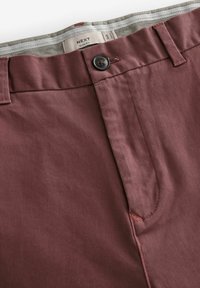 Pantalones marinos ajustados con cierre de botón, trabillas para cinturón y una cinturilla interior texturada de rayas grises. Tejido suave con costuras mínimas.