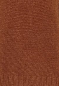 Hnědá pletená tkanina střední tloušťky, s hladkým povrchem. Jemné odstíny se liší, žádné výrazné vzory ani hardware nejsou viditelné.