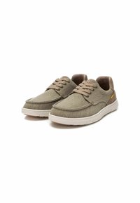 Zapatillas de lona en verde olivo con acentos grises, que presentan un diseño de cordones, una suela de goma y detalles de costura en contraste.