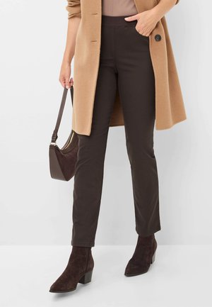 Bruine maatpakken met een getailleerde taille, zachte stof en een slanke pasvorm, gecombineerd met donkere suède enkelaarsen en een lichtbruine jas.