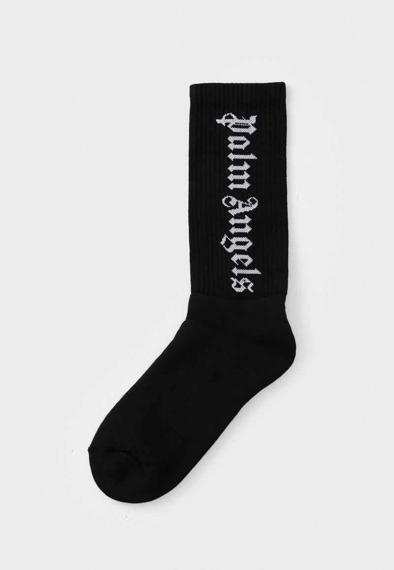 Meias pretas com textura canelada, apresentando texto branco com a inscrição "Palm Angels". O design inclui um comprimento crew e uma textura suave e macia.