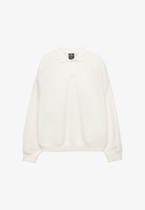 Világos bézs pulóver, polo gallérral, hosszú ujjakkal és bordázott mandzsettákkal. Puha anyagból készült, laza szabású, háromgombos felsőrésze van.