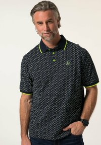 Polo de color azul marino con un patrón floral, detalles en verde lima en el cuello y las mangas, de mangas cortas y con dos botones en el cuello.