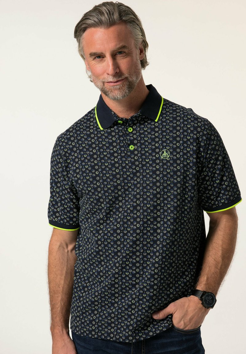 Polo de color azul marino con un patrón floral, detalles en verde lima en el cuello y las mangas, de mangas cortas y con dos botones en el cuello.