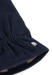 Close-up of navy blue glove cuff with elastic detail and small silver button showing embossed design.