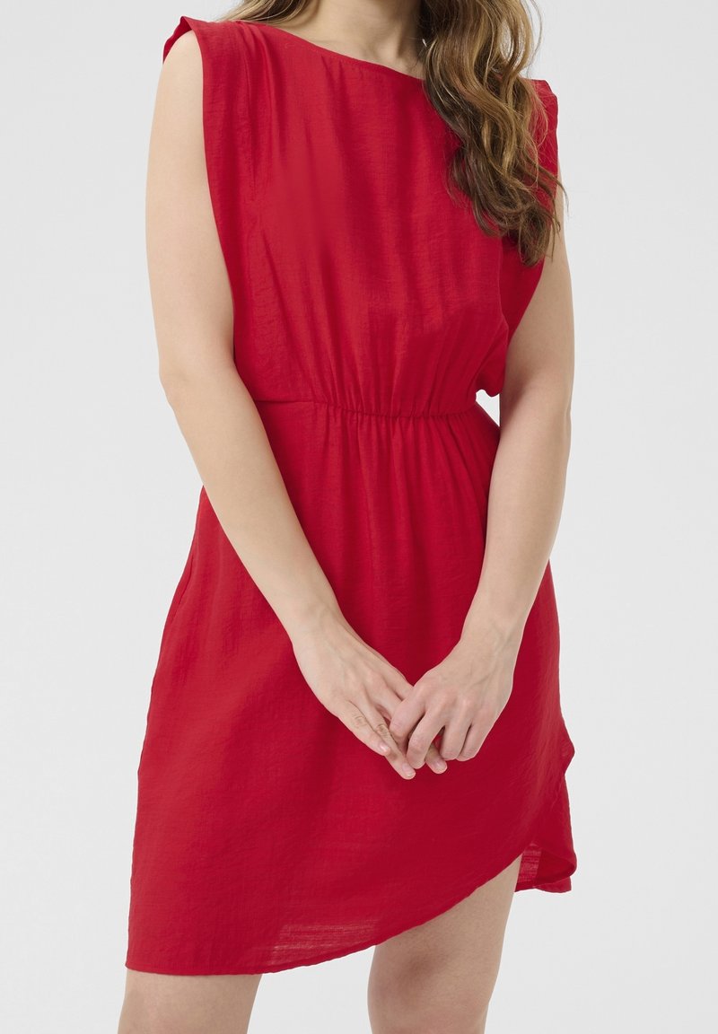 Robe rouge à manches courtes, coupe ample avec une taille élastique. Présente un ourlet légèrement asymétrique et une texture froissée.
