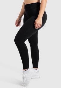 Hoge taille zwarte leggings van rekbaar materiaal met een gladde textuur, met een naadloos ontwerp en ze komen boven de enkel.