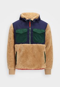 Giacca con cappuccio caratterizzata da parte superiore blu scuro e pile strutturato color sabbia; tasche verdi; chiusura con zip con accento rosso; polsini a coste.