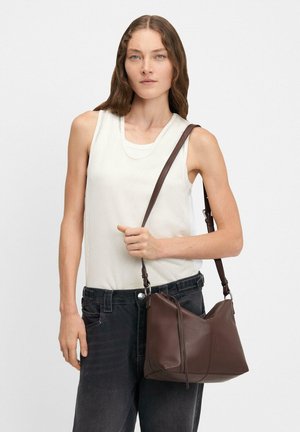 Brązowa skórzana torebka o luźnym fasonie, z długim regulowanym paskiem, minimalistycznymi akcentami i gładką teksturą.