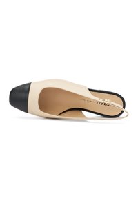 Scarpa slingback in pelle beige con punta rotonda nera; presenta un'ampia apertura e una sottile cinghia sul tallone per una calzata sicura.