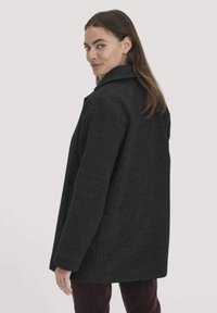 Grauer Wollmantel mit lockerer Passform, weitem Kragen und zwei Seitentaschen, mit einer strukturierten Oberfläche und ohne sichtbare Knöpfe oder Beschläge.