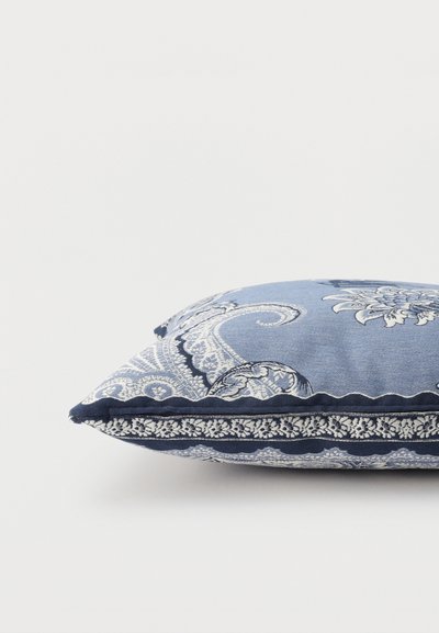 Coussin décoratif bleu avec motifs cachemire et floraux blancs et bleu marine, présenté à plat sur un fond blanc.