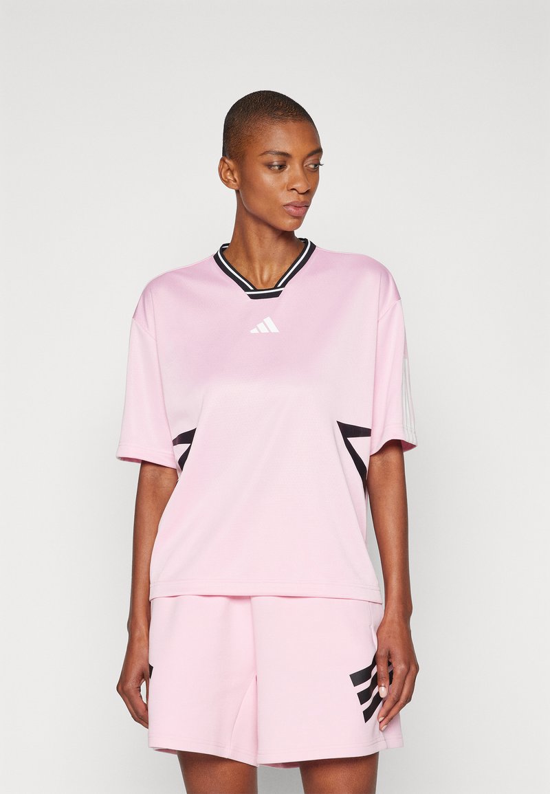 Camiseta deportiva rosa con escote en V, ribete negro y detalles negros en un diseño deportivo; combinada con pantalones cortos rosas a juego.