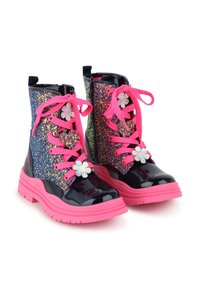 Glitrende ankelstøvler med marineblå lakkfinish, rosa snøring og blomsterdekorasjoner. Sålen er tykk og rosa, med et teksturert gummigrep.