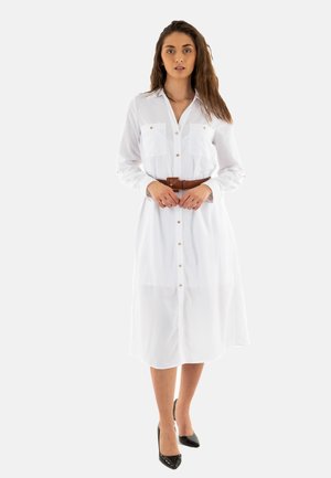 Robes chemises blanches à boutons avec deux poches poitrine, manches longues et une ceinture marron. Dotée d'un col classique et de boutons dorés.