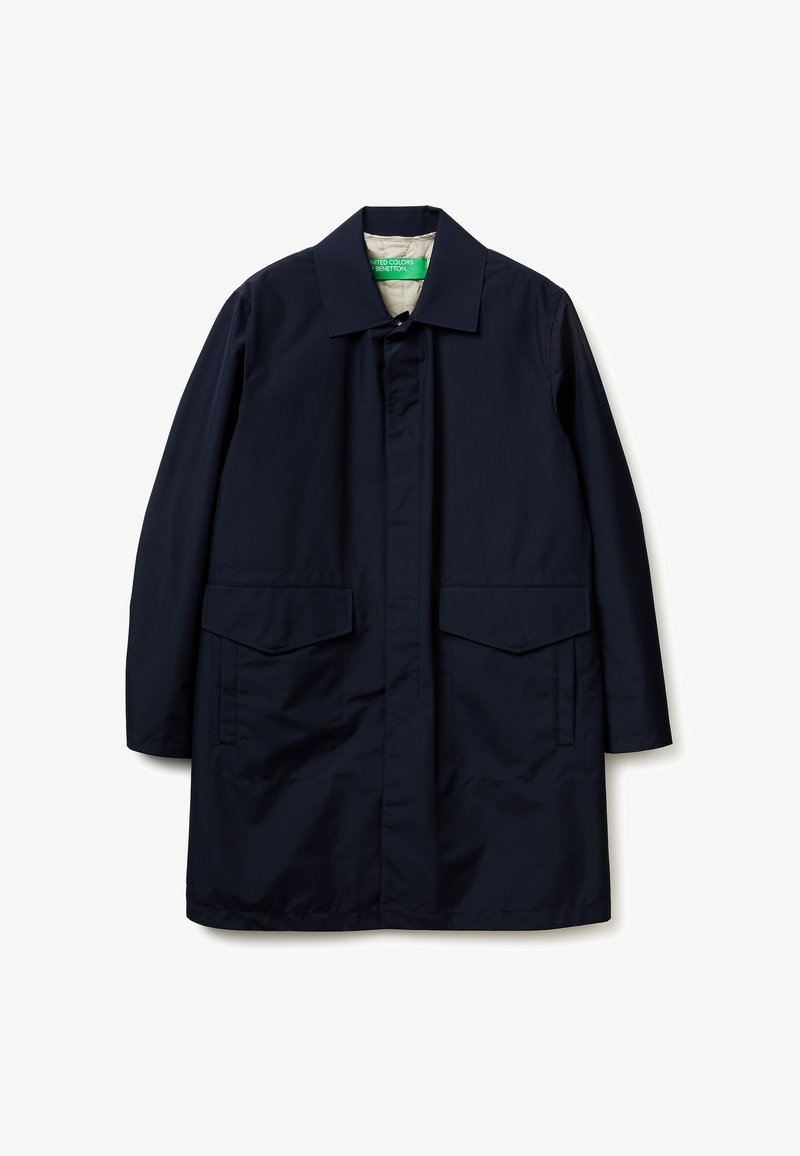 Marineblauwe lange jas met puntige kraag, verborgen knopen aan de voorkant en twee grote klepzakken aan de voorkant, plat neergelegd op een witte achtergrond.