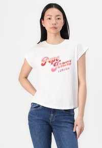 White cotton t-shirt with rolled sleeves, featuring a colorful "Pepe Jeans London" graphic across the chest. Worn with blue jeans.