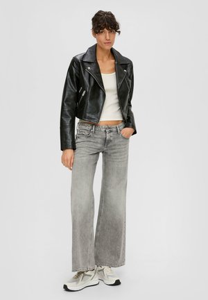 Black leather cropped biker jacket over a white tank top, paired with gray wide-leg jeans and gray sneakers with accent details.