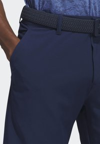 Tamsiai mėlynos kelnės su švelnia tekstūra, su austu diržu tos pačios spalvos. Yra �šoninės kišenės ir aptemptas kirpimas.