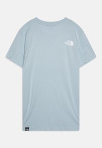 Helles blaues T-Shirt mit kurzen Ärmeln aus weichem Stoff, das auf der oberen Rückseite ein weißes Logo und ein schwarzes Etikett am unteren Ende aufweist. Rundhalsausschnitt.