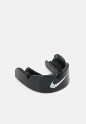 Črn plastični zaščitnik za usta s ukrivljeno obliko, s prominentnim belim logotipom Nike na sprednji strani in dvema režama za zobe.