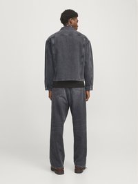 Denimjakke i falmet svart med en avslappet passform, paret med matchende løstsittende jeans. Har klassisk søm og to baklommer.