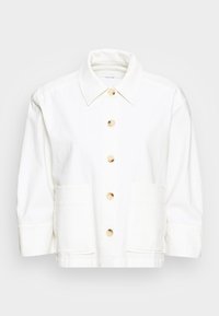 Chaqueta de mezclilla blanca con grandes bolsillos frontales, cuello puntiagudo y botones de color claro. Tejido texturizado con un ajuste relajado.