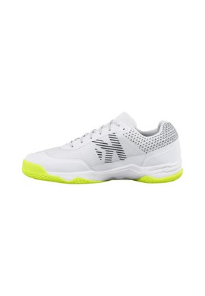 Zapatilla deportiva blanca con suela de color amarillo neón, patrón abstracto negro en el lateral, y pequeño patrón de cruces negras alrededor del área del talón.