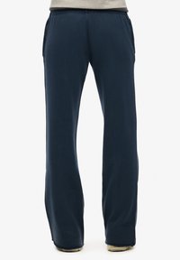 Granatowe, luźne spodnie o gładkiej teksturze, z elastycznym pasem i kieszeniami bocznymi. Prosty krój nogawki z delikatnym rozszerzeniem na dole.