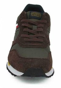 Sneaker marrone e verde realizzato in materiali scamosciati e in rete, dotato di lacci marroni, strisce rosse e blu, e una suola in gomma con accenti gialli.