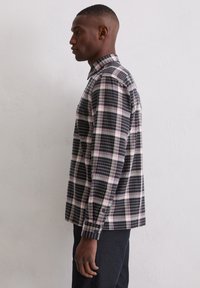 Herren-Karohemd zum Knöpfen in Schwarz, Weiß und Pink. Mit langen Ärmeln und einem strukturierten Kragen. Hergestellt aus leichtem Stoff.