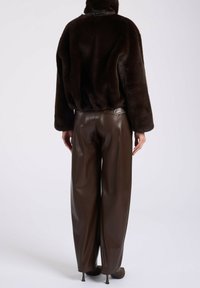 Bruine nepbontjas met een ontspannen pasvorm, elastische zoom, gecombineerd met donkerbruine high-waisted leren broeken, gladde textuur, wijde pijpen.