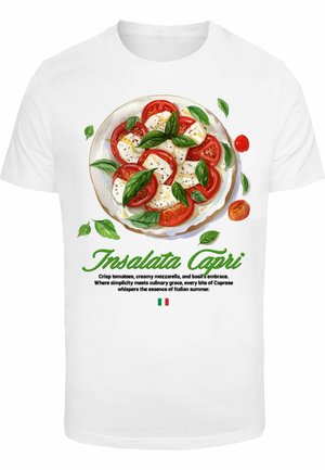 T-shirt blanc arborant un graphique d'une salade Caprese avec des tomates rouges, de la mozzarella blanche et des feuilles de basilic vertes. Le texte en dessous décrit le plat.