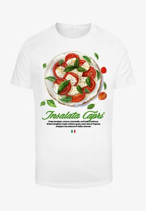 Valkoinen t-paita, jossa on graafinen kuva Caprese-salaatista, jossa on punaisia tomaatteja, valkoista mozzarella-juustoa ja vihreitä basilikanlehtiä. Teksti alla kuvaa annosta.