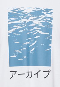 Camiseta blanca con un gráfico de ondas de agua azul encima de un texto negro que dice "アーカイブ." El diseño tiene una textura suave y plana.